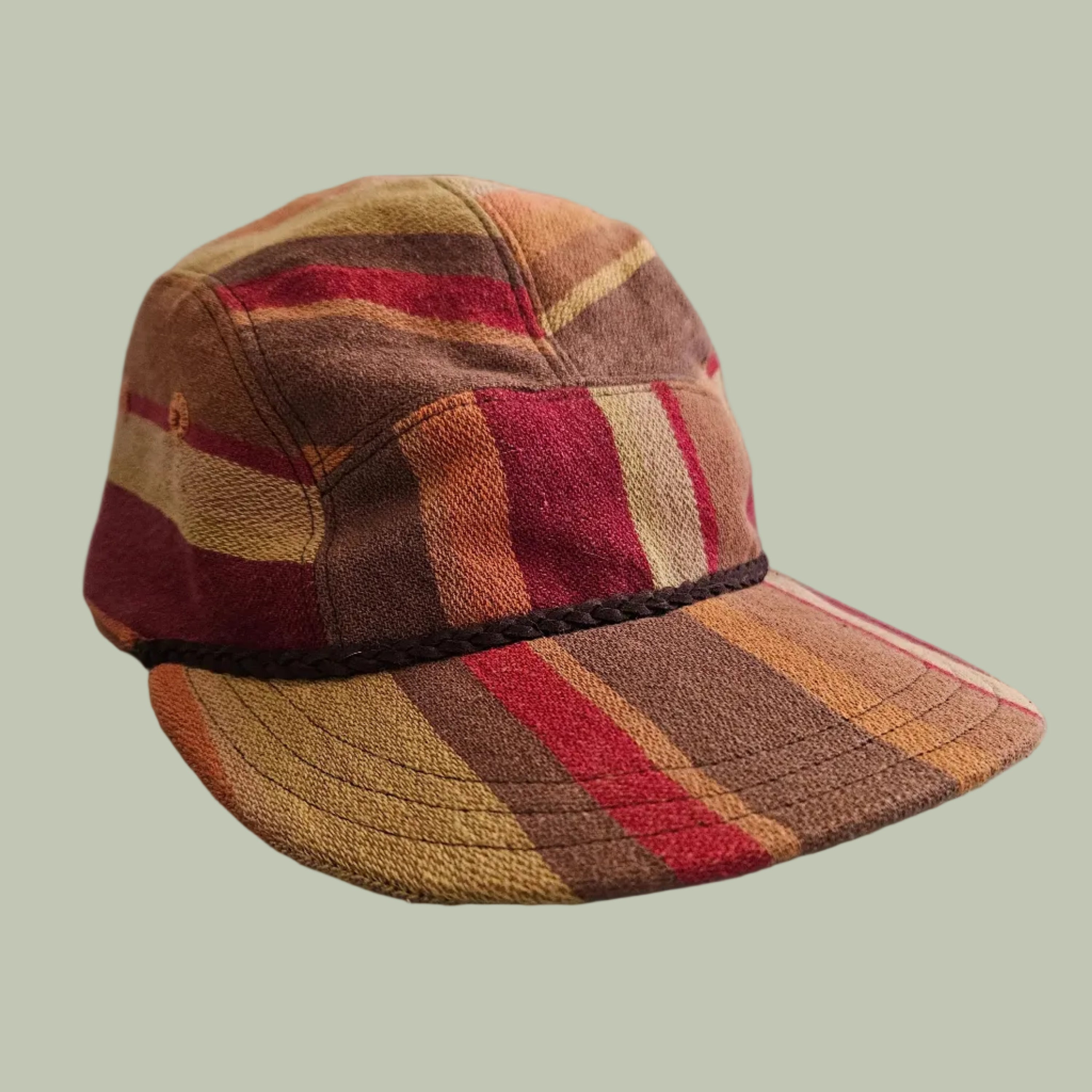 a red brown cream and orange striped hat with a leather braid trim detail
