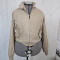 Front of a beige jacket with ribbed collar, metal zipper, and button pockets