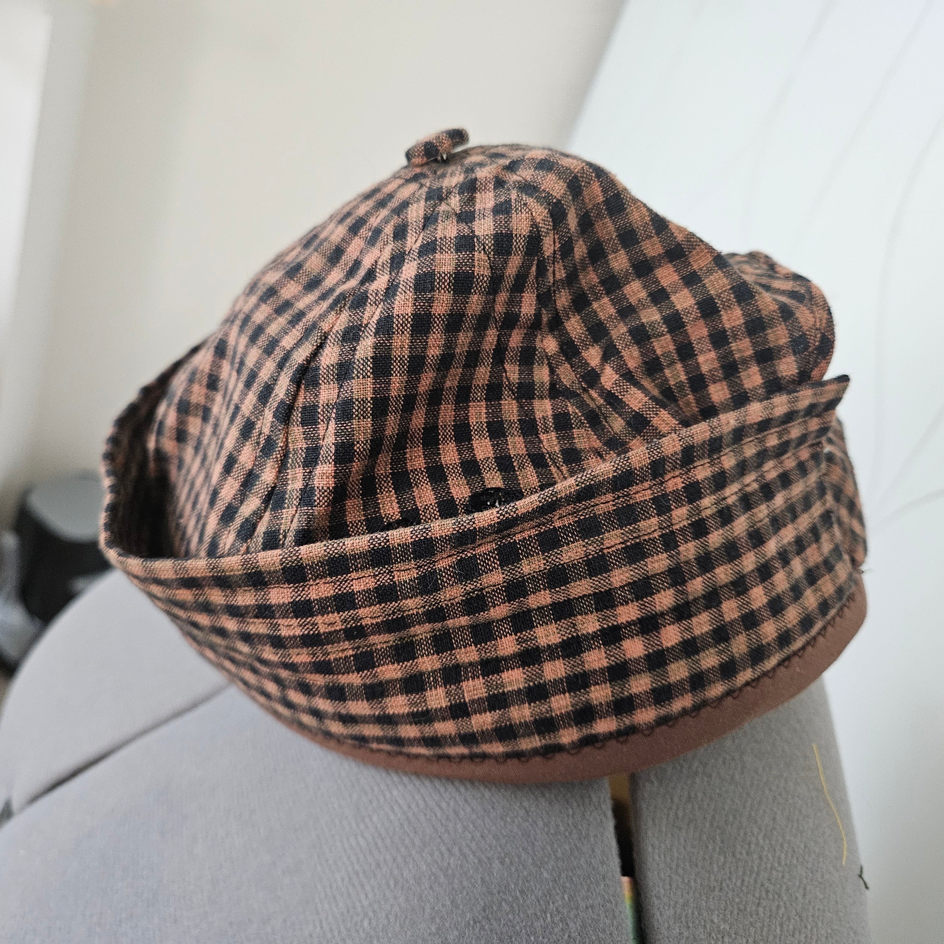Side view of brown and black gingham brimless cap