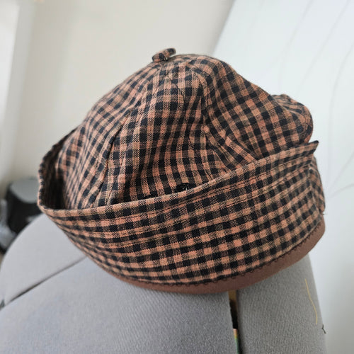 Side view of brown and black gingham brimless cap