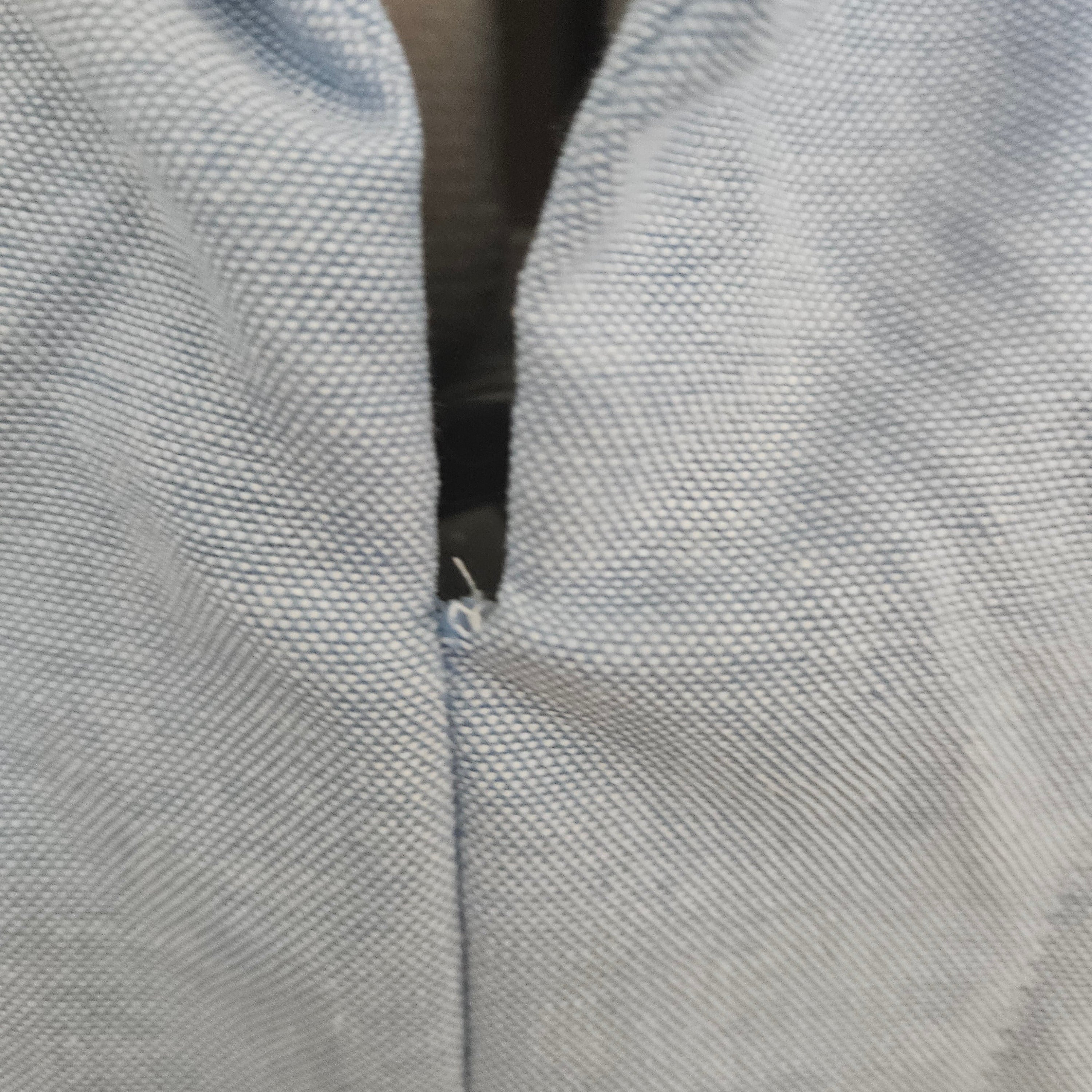 Close up of loose thread at the collar on a light blue shirt