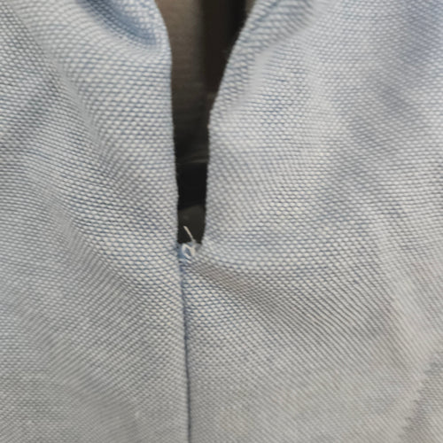 Close up of loose thread at the collar on a light blue shirt