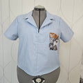 Front view of light blue shirt with open collar and cat print patch pocket