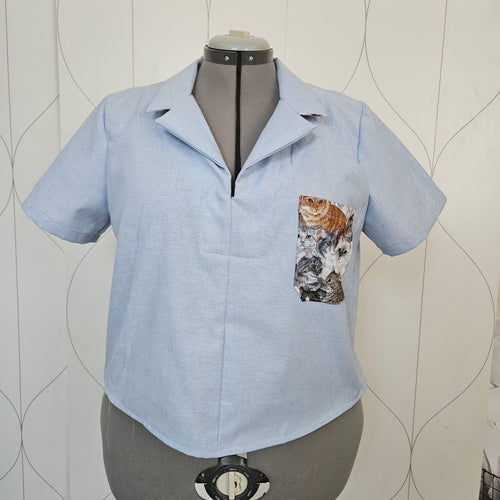 Front view of light blue shirt with open collar and cat print patch pocket