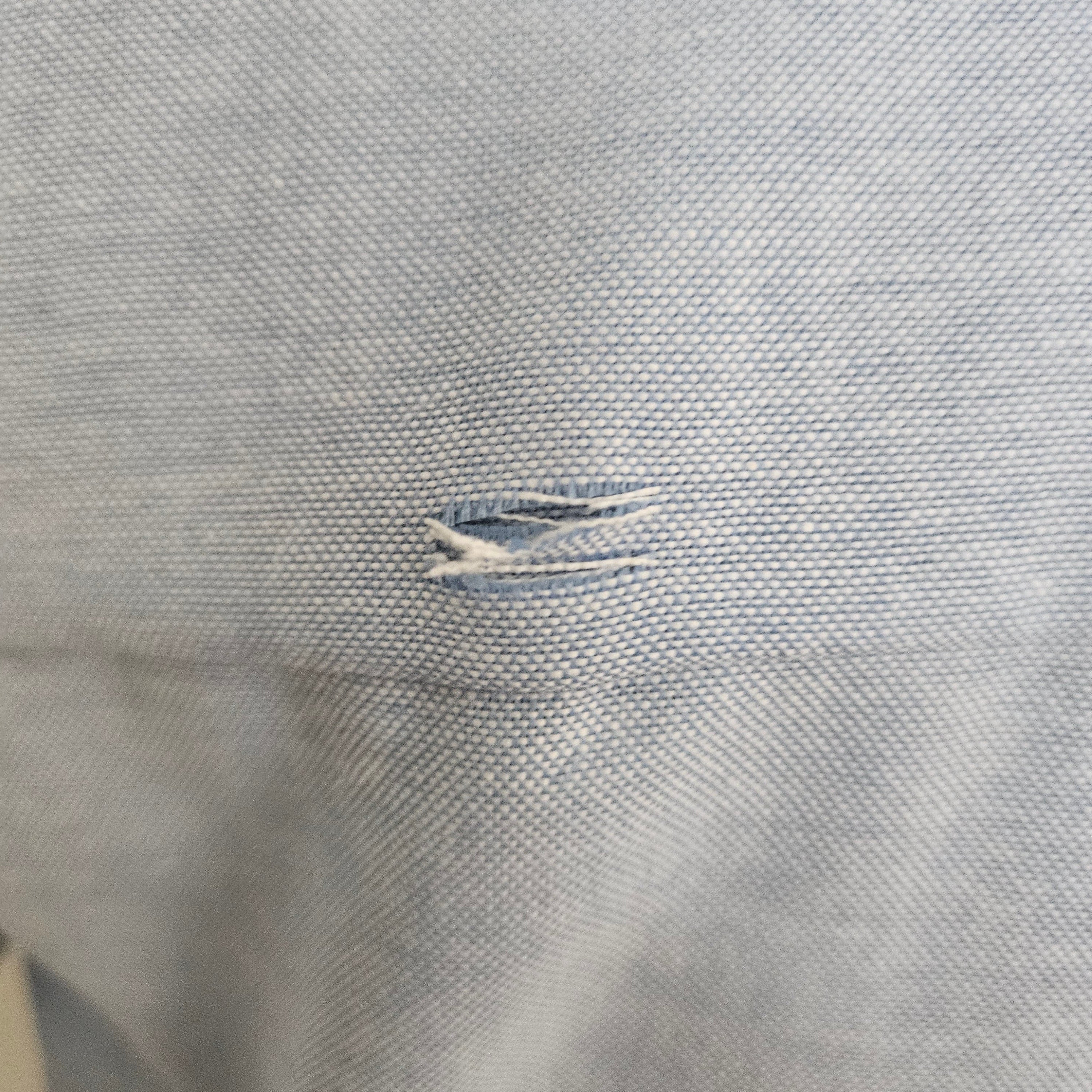 Close-up of small hole on the back of light blue shirt