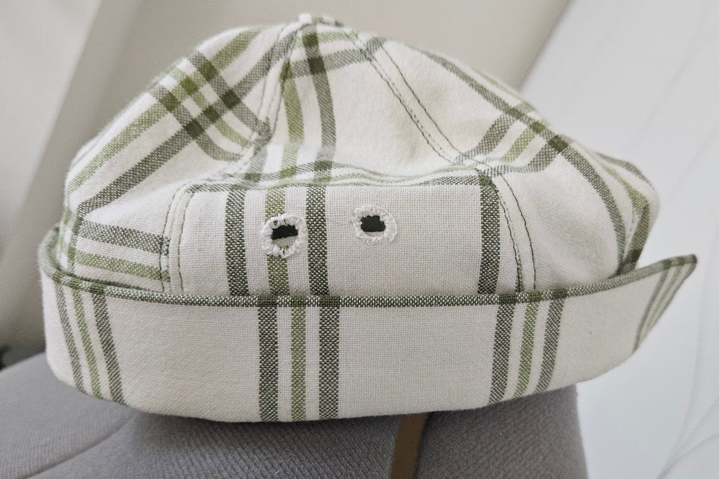 Hand sewn eyelets on green and white brimless cap