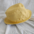 Yellow bucket hat on a white fabric background